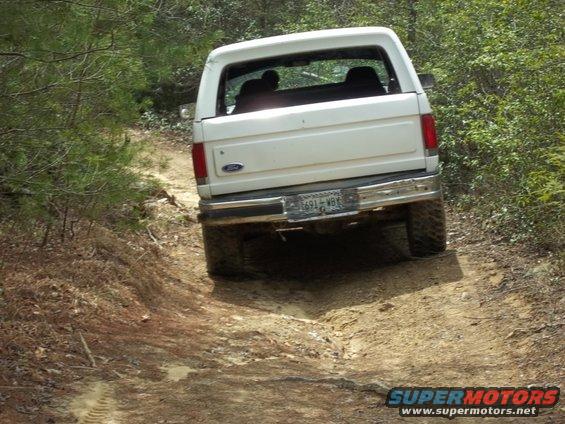 White Ford Bronco from the rear, driving off-road on a dirt path