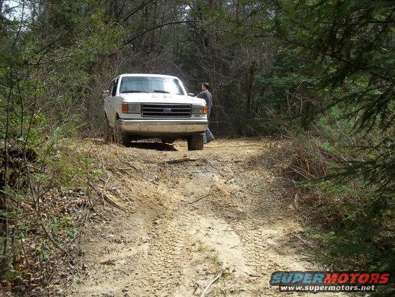 White Ford F-Series truck on a dirt path in the woods