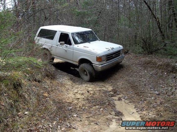 White 1990 Ford Bronco on a muddy trail