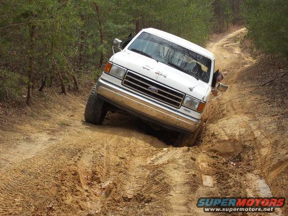 White 1990 Ford Bronco navigating a muddy off-road trail