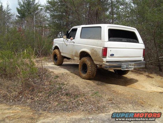 White 1990 Ford Bronco driving on a dirt trail