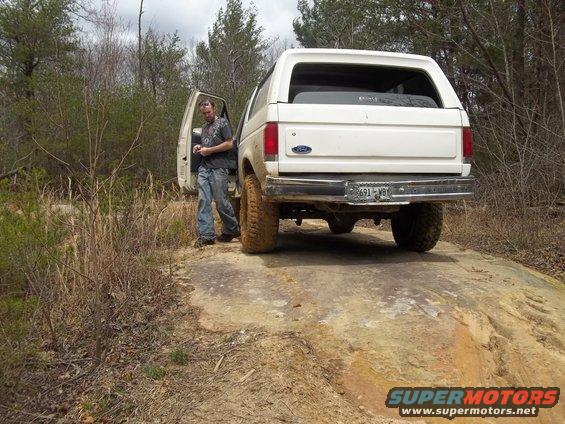 White 1990 Ford Bronco with driver's door open, parked on a rocky trail