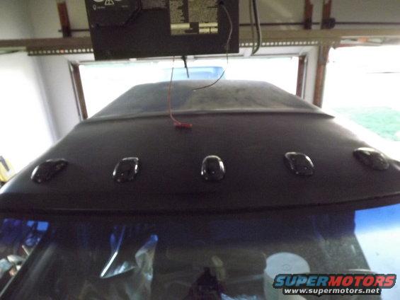 Top of vehicle roof with five clearance lights and a red wire hanging down