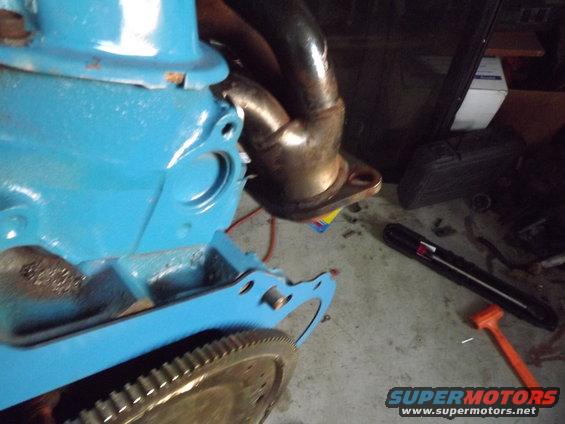 Blue engine block with exhaust manifold and flywheel teeth