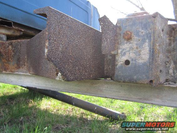 rusted metal frame and bracketry on a vehicle, blue paint visible above