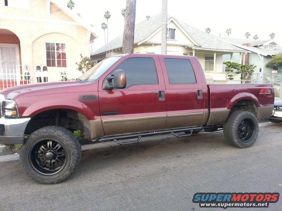 Red and brown Ford F-250 Super Duty pickup truck, four doors, lifted with black wheels