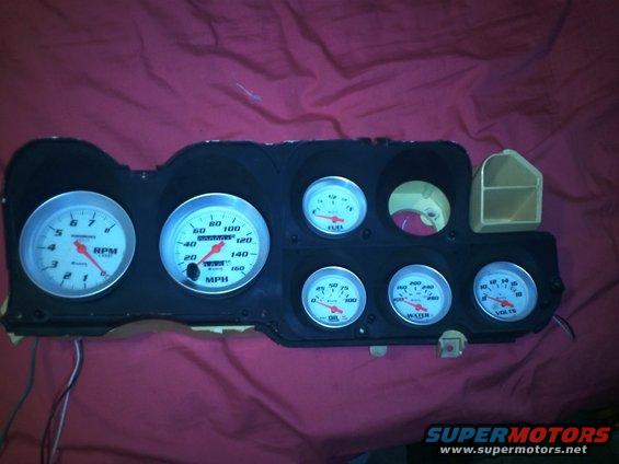 Instrument cluster with RPM, MPH, Fuel, Oil, Water, and Volt gauges against a red fabric background
