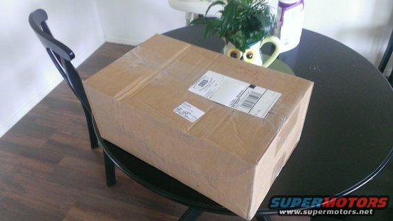 Cardboard box with shipping labels on a round black table, next to a black chair
