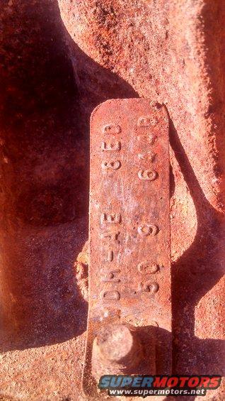 Close-up of a rusty metal plate with stamped numbers: 338, 6419, DH-1E-609
