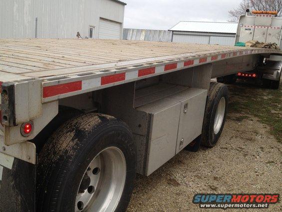 Flatbed trailer side view with red reflectors and toolboxes