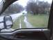 2003 Ford Crown Victoria - The view from the driver's seat shows a rainy day with water on the road and grass.