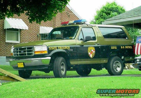 Green and black Ford Bronco with 'STATE TROOPER' and 'K-9 PATROL' markings, police lights on top