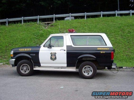 Side view of a 1994 Ford Bronco police vehicle with "SHERIFF" on the fender and "EMERGENCY 9-1-1" on the rear quarter panel