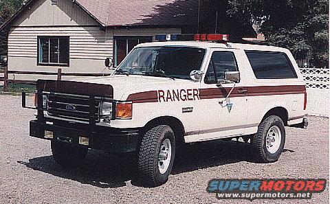 White Ford Bronco with red and brown stripes, says RANGER on the side. Has a push bar and light bar on top