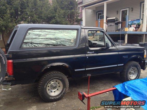 Side view of a black 1996 Ford Bronco with a spare tire on the rear