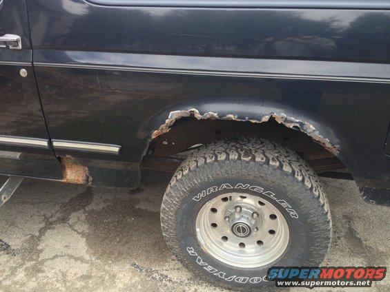 Dark blue Ford Bronco rear fender with significant rust and a Goodyear Wrangler tire