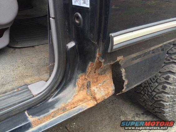 Black 1996 Ford Bronco door sill with significant rust and tire visible