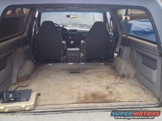 Interior of a 1992 Ford Bronco with worn carpet, two front seats, and a center console