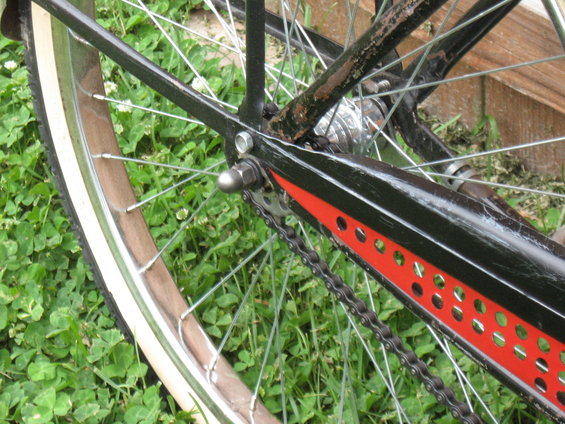 Bicycle rear wheel with whitewall tire and black frame with red accents