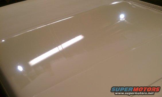 Close-up of a light-colored vehicle hood with reflections
