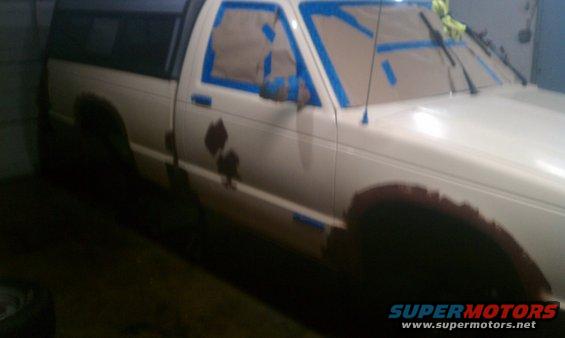 1991 Chevrolet S10 pickup truck with windows taped off for painting, showing rust spots