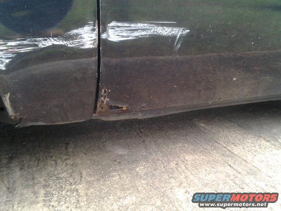 Dark colored car door and rocker panel with rust and scratches