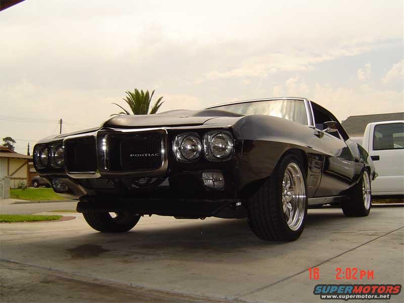 Black 1969 Pontiac Firebird with chrome grille and aftermarket wheels, parked on a driveway