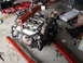 1992 Ford Taurus - An engine is suspended by a hoist, resting on a stand in a cluttered garage environment.