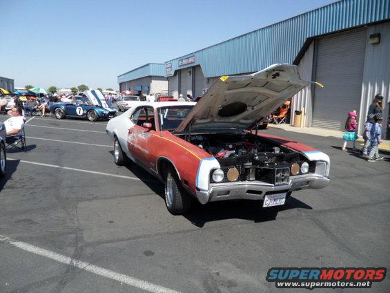 Red and white car with hood open, showing engine. License plate reads CUM296