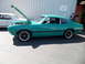 1973 Ford Ranchero - A teal 1970 Ford Maverick coupe is parked outside a building with its hood open, next to a white car.