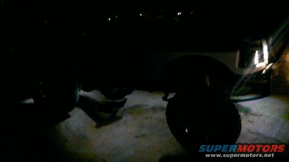 SUV tire and fender at night. Supermotors.net logo visible