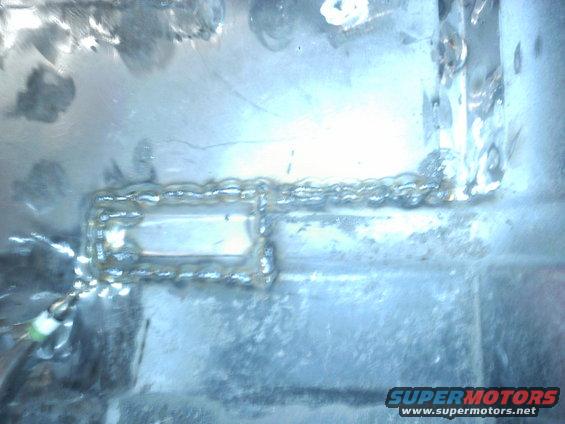 Close-up of a metal frame with visible welding. A small green wire is attached