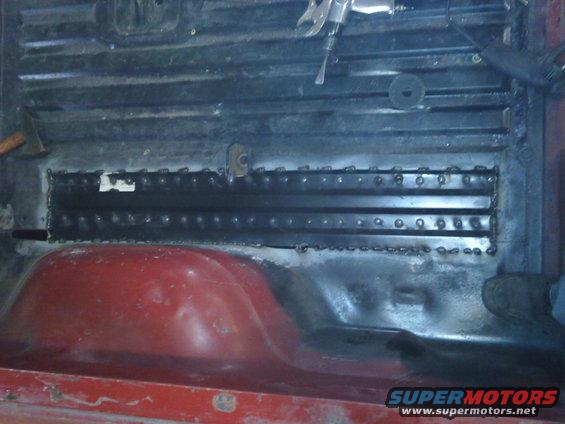 Interior view of vehicle floor with metal reinforcement and red wheel well