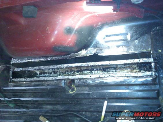 rusted metal frame with wires and a yellow loop, Supermotors.net logo visible