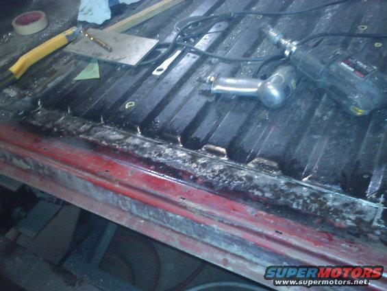 Red truck bed with a drill, air hammer, and tape