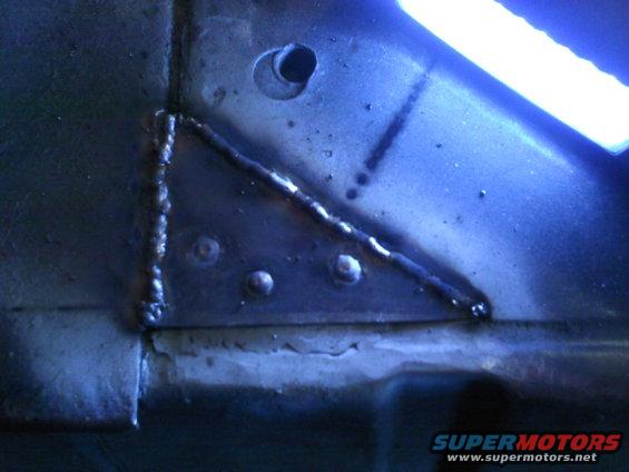 Close-up of welded metal on a vehicle frame. Shows rivets and a drilled hole