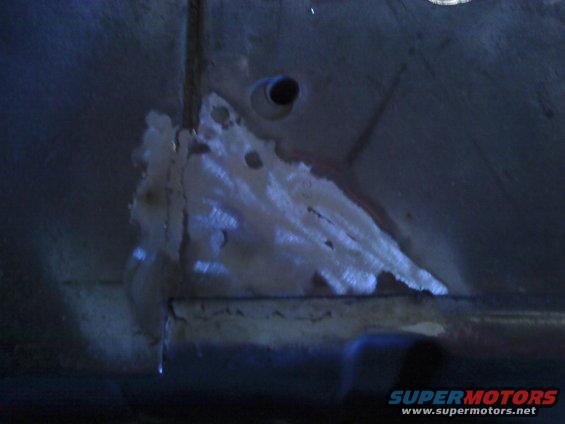 Rusted metal panel with holes and a small pipe fitting