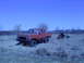 1978 Ford Bronco - A red pickup truck is parked in a field, tethered to a green tractor.