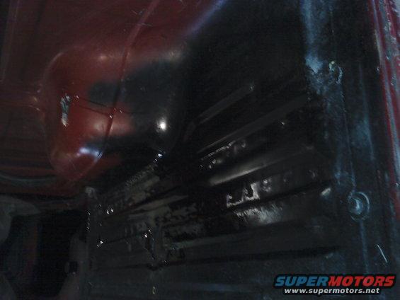 Red and black vehicle interior floor with visible structural ribs and a circular wheel well