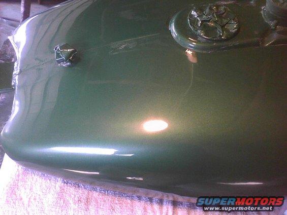 Green car hood with a silver emblem covered in tape