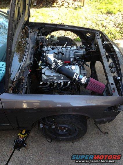 Engine bay with supercharger and red air filter, front fender removed