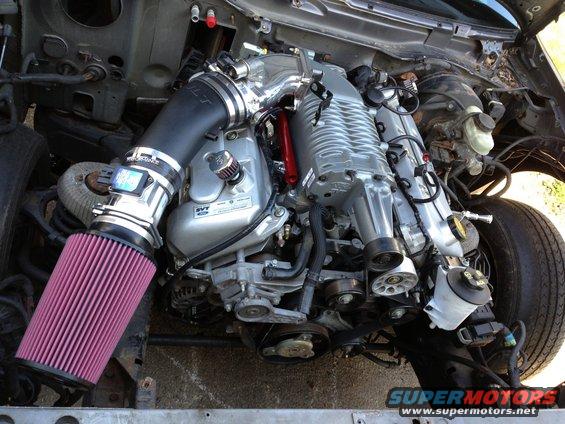 Supercharged V8 engine with large pink air filter and custom intake piping