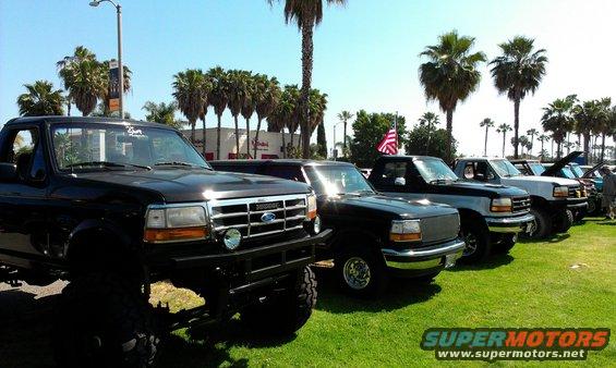 Black Ford F-250 pickup truck with lifted suspension parked in a line with other trucks
