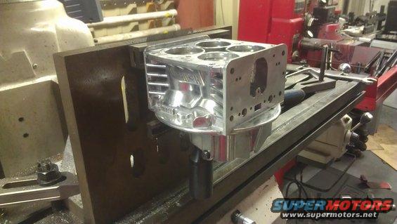 Aluminum engine block being machined on a milling machine. It has four cylinders visible on top
