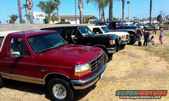Red 1992-1996 Ford Bronco parked in a line with other trucks and SUVs