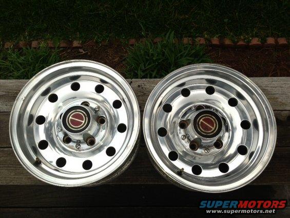 Two polished aluminum wheels with red and black Ford center caps