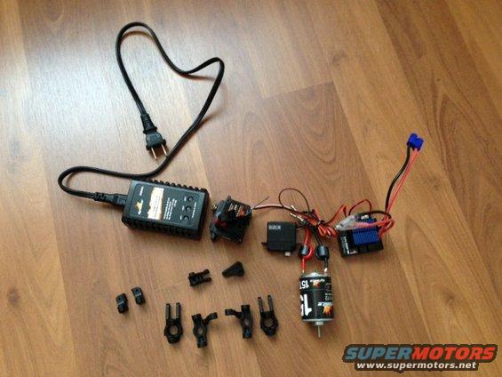 RC car motor, ESC, servo, and charger on wooden floor