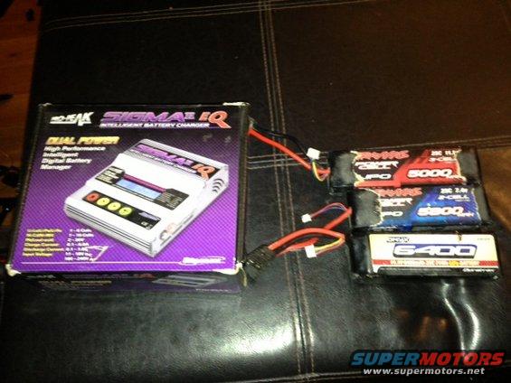 Boxed dual power intelligent battery charger next to three RC LiPo batteries