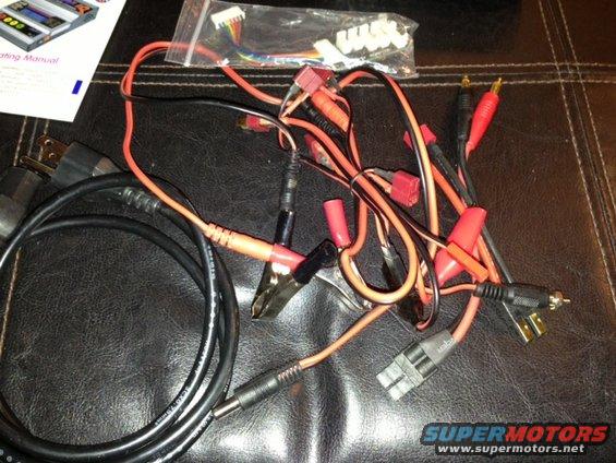 Battery charger cables and manual on a dark textured surface