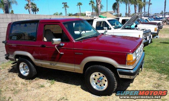 Red Ford Bronco II with tan trim, parked on grass